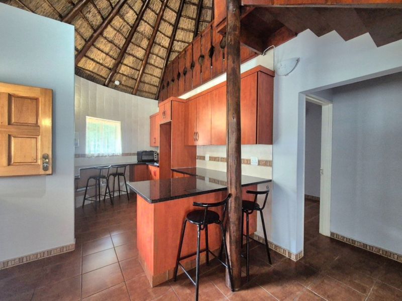 Kitchen featuring wooden cabinetry, granite countertops, a breakfast bar, and a unique high-pitched thatch roof ceiling.