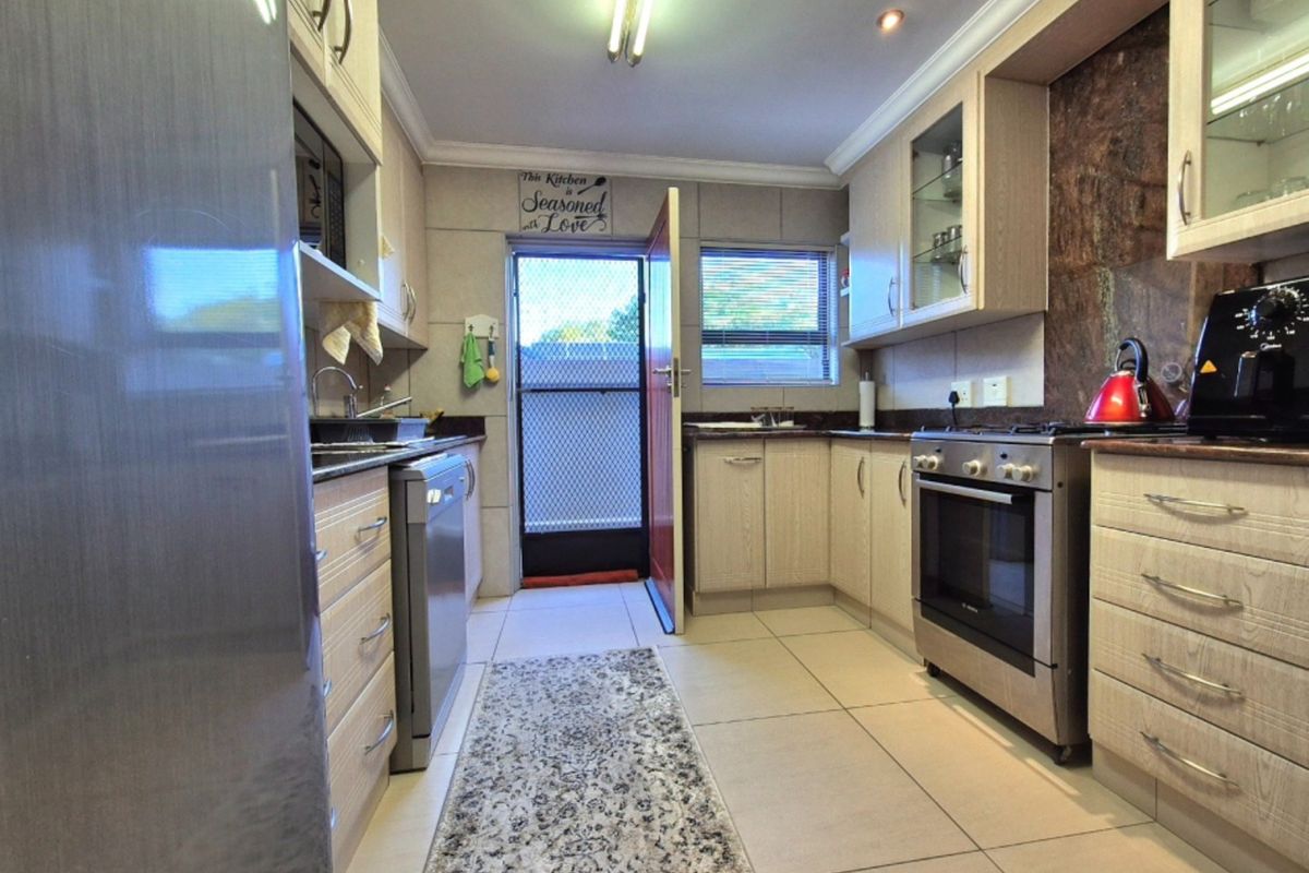 Functional kitchen featuring light wood cabinetry, granite countertops, stainless steel oven, gas hob, and tiled flooring with direct access to the exterior.
