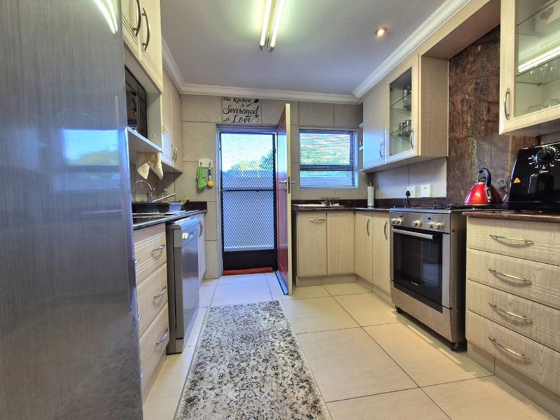 Functional kitchen featuring light wood cabinetry, granite countertops, stainless steel oven, gas hob, and tiled flooring with direct access to the exterior.
