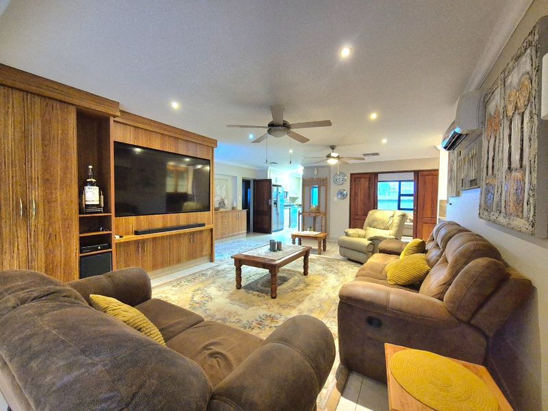 Spacious living room featuring built-in wooden cabinetry, recessed lighting, ceiling fans, and air conditioning, with tiled flooring throughout.