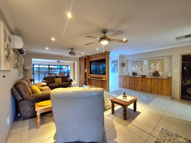 Spacious living room featuring tiled flooring, recessed lighting, ceiling fans, and extensive built-in wooden cabinetry for storage and media display.