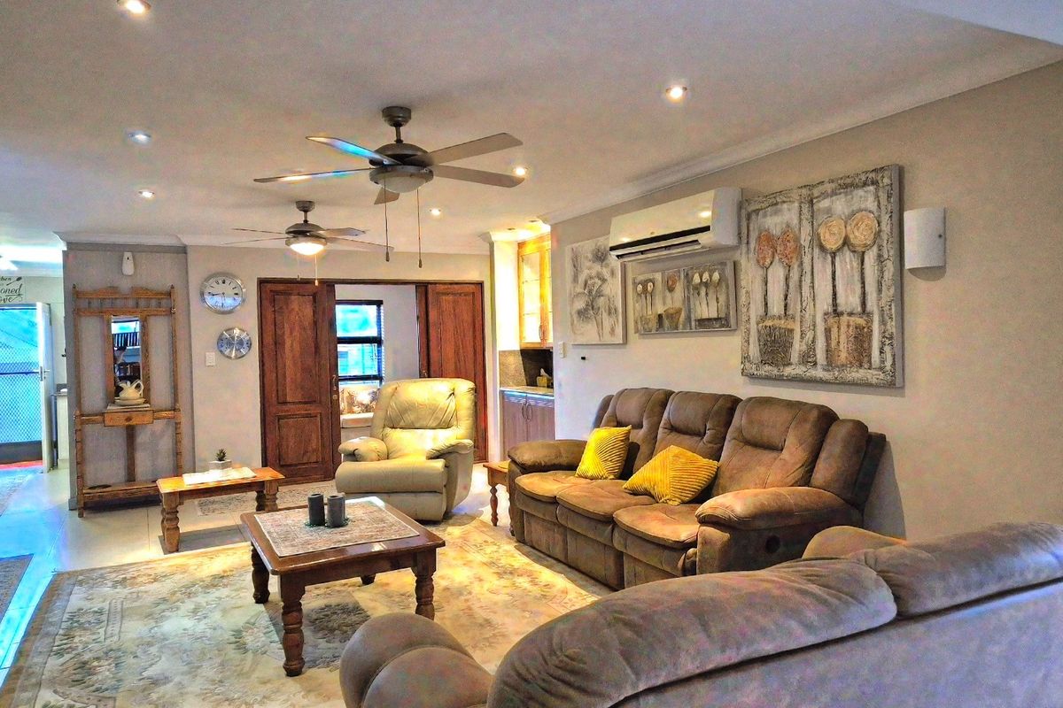 Spacious living room featuring tiled flooring, recessed downlights, ceiling fans, and a wall-mounted split-system air conditioning unit.