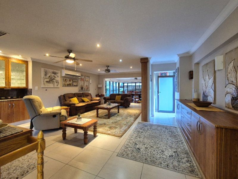 Spacious open-plan living area featuring tiled floors, recessed lighting, ceiling fans, and built-in cabinetry, offering a versatile layout with direct access to the exterior.