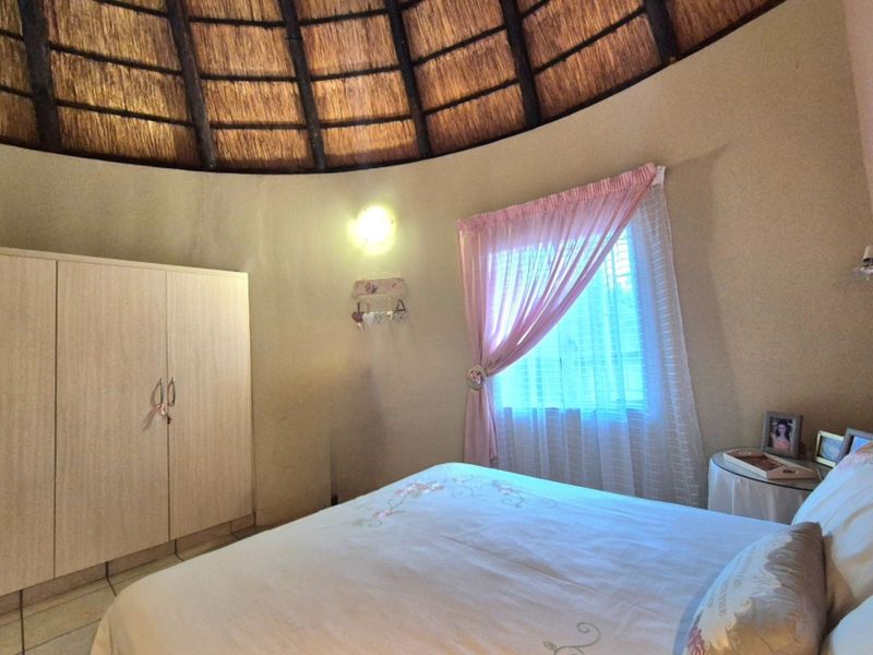 A bedroom featuring a unique circular layout with a traditional thatched roof ceiling, tiled flooring, and a built-in wardrobe.