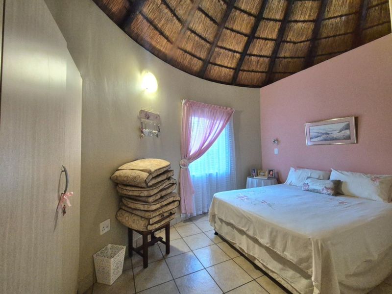 A bedroom featuring a unique circular layout with a traditional thatched roof, tiled flooring, and a built-in wardrobe.