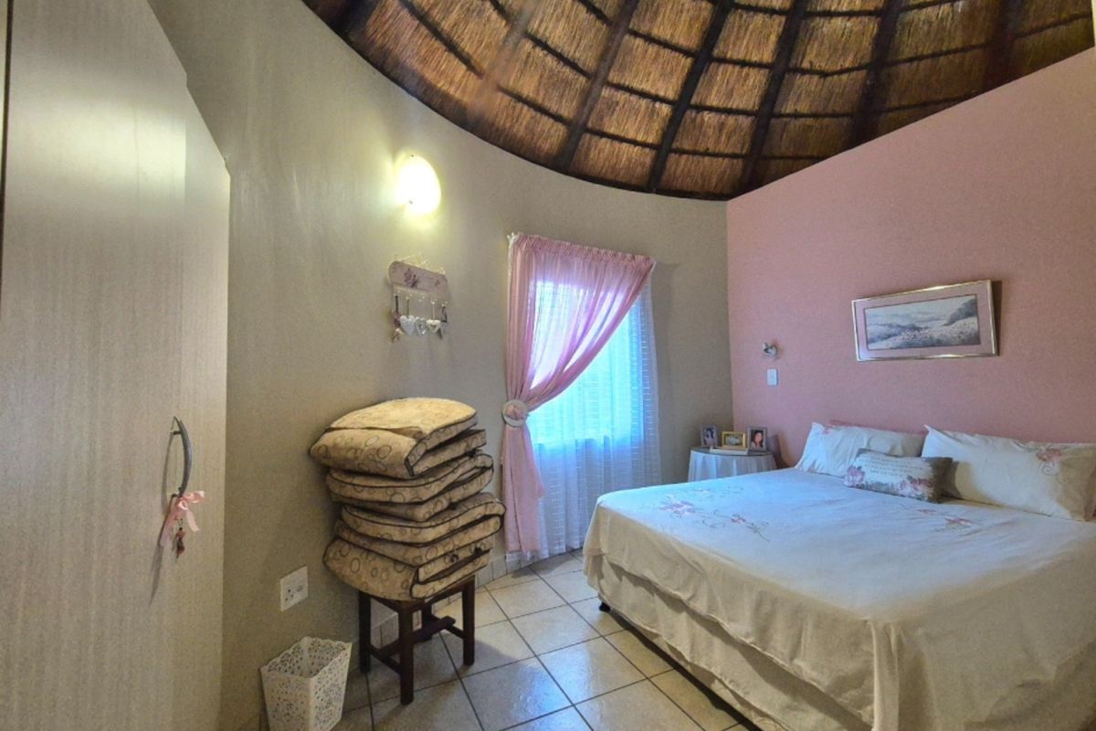A bedroom featuring a unique circular layout with a traditional thatched roof, tiled flooring, and a built-in wardrobe.