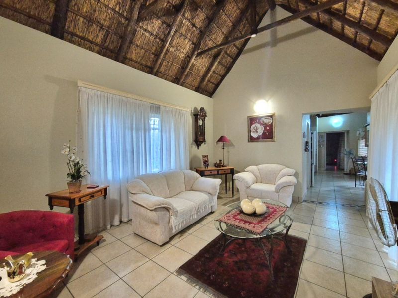 Spacious living room featuring a high vaulted thatched ceiling with exposed timber rafters and neutral tiled flooring.