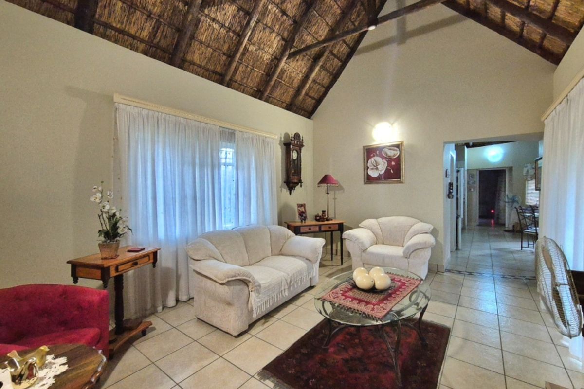 Spacious living room featuring a high vaulted thatched ceiling with exposed timber rafters and neutral tiled flooring.