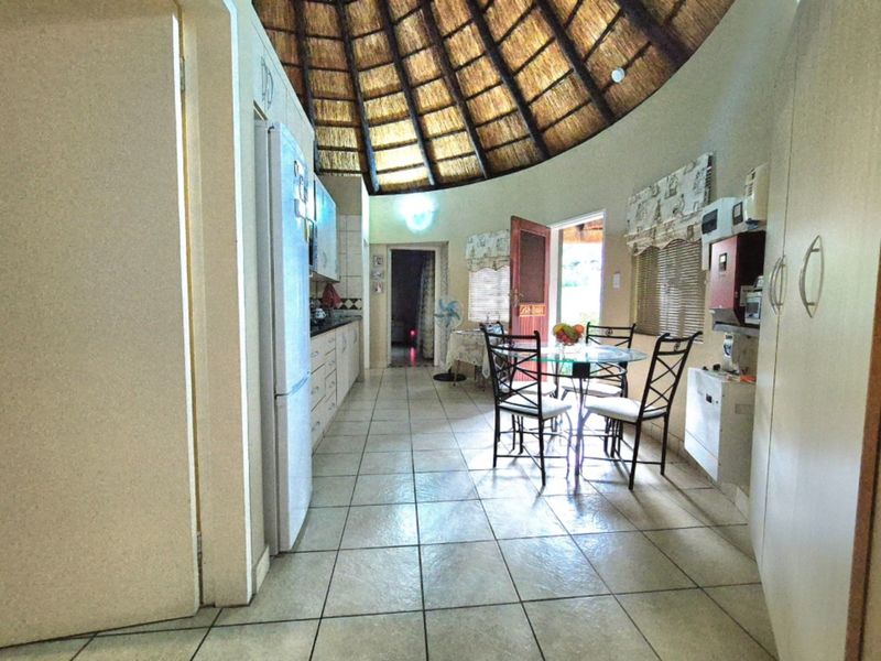 Open-plan kitchen and dining area featuring a unique vaulted thatched ceiling and tiled flooring, providing a rustic and spacious living environment.