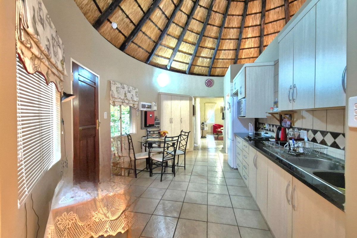 A unique kitchen area featuring a high thatched ceiling, tiled flooring, and built-in cabinetry with granite countertops.
