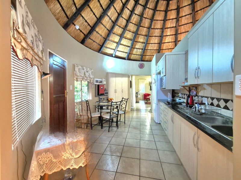 A unique kitchen area featuring a high thatched ceiling, tiled flooring, and built-in cabinetry with granite countertops.