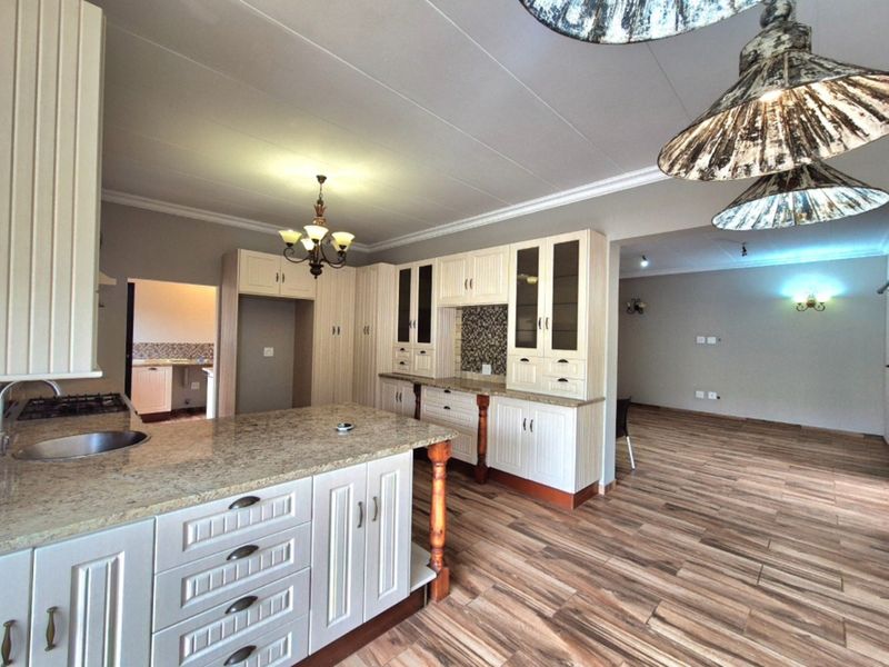 Spacious open-plan kitchen featuring granite countertops, ample built-in cabinetry, and a gas hob, seamlessly flowing into the adjacent living area.