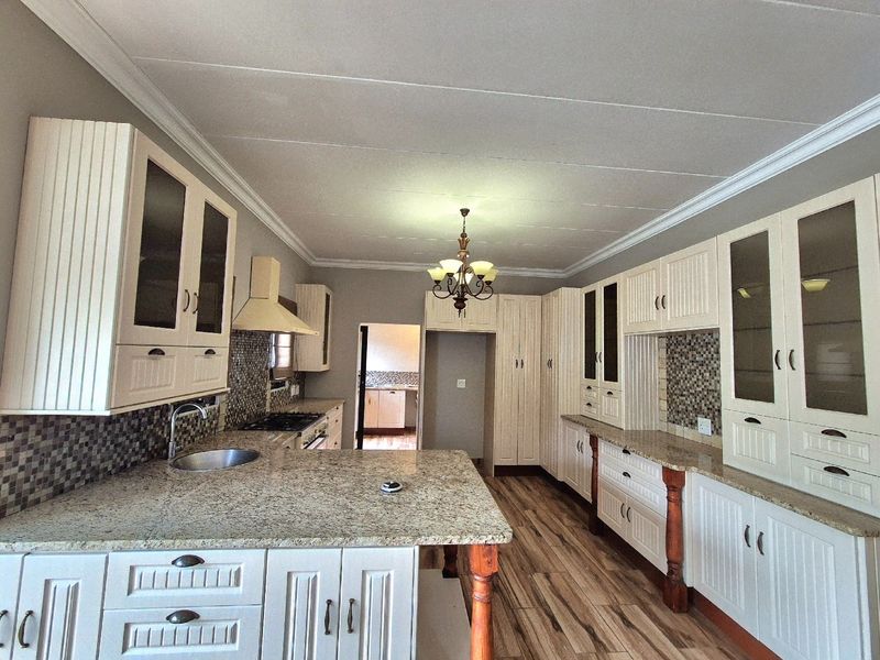 Spacious kitchen featuring extensive built-in cabinetry, granite countertops, mosaic tile backsplash, and integrated appliances, offering a functional and well-maintained culinary space.
