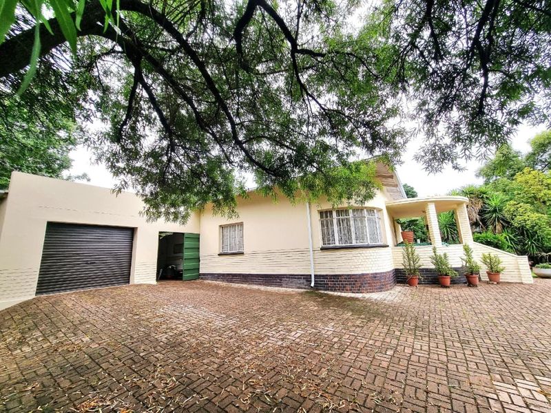Front elevation of a house featuring a brick paved driveway, a garage with a roller shutter door, and a covered porch area.