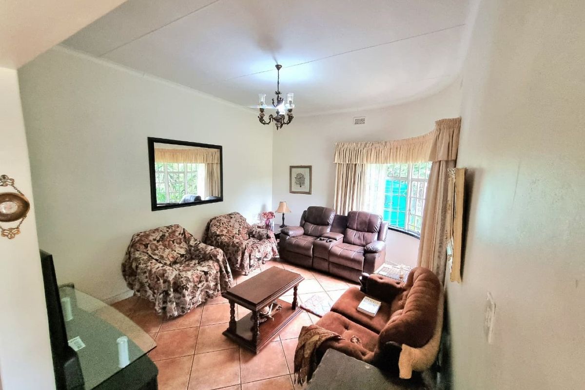 A living room featuring tiled flooring and natural light from large windows with curtain rails.