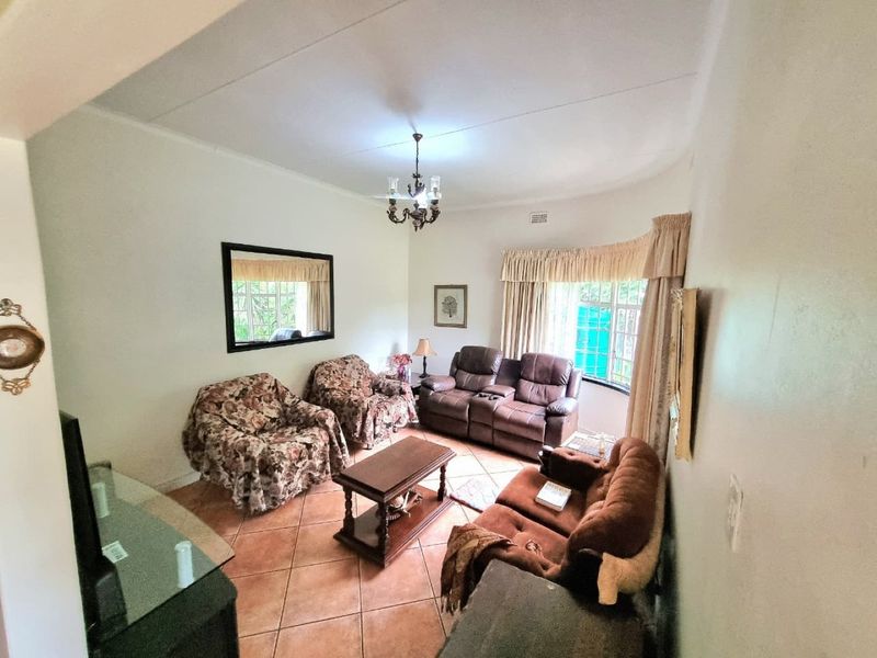A living room featuring tiled flooring and natural light from large windows with curtain rails.