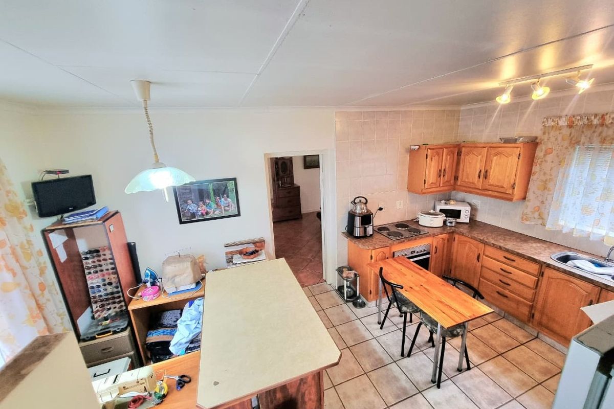 A functional kitchen featuring wooden cabinetry, laminate countertops, tiled flooring, and a built-in oven and hob, offering a traditional layout with ample storage.