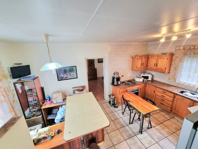 A functional kitchen featuring wooden cabinetry, laminate countertops, tiled flooring, and a built-in oven and hob, offering a traditional layout with ample storage.