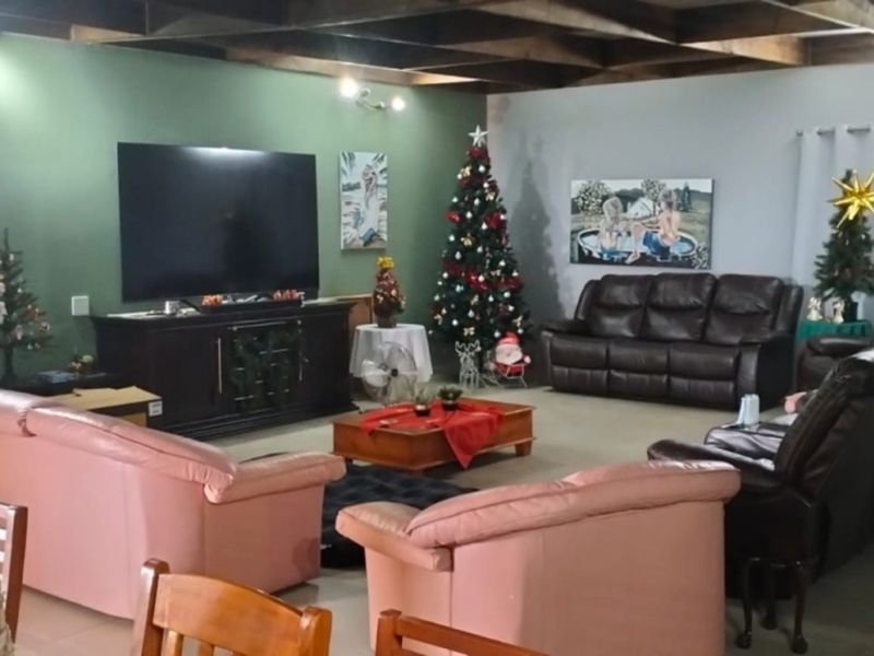 Spacious living room featuring exposed timber ceiling beams and tiled flooring, offering a comfortable and functional area for relaxation.