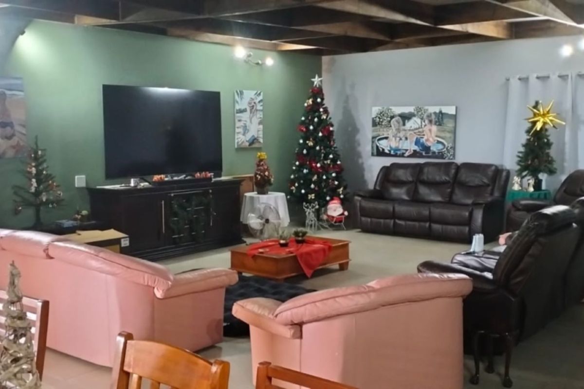 Spacious living room featuring exposed timber ceiling beams and tiled flooring, offering a comfortable and functional area for relaxation.