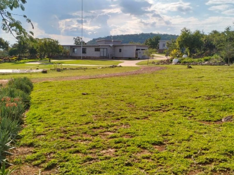 A wide-angle view of the farm property featuring a paved driveway leading to the main residence set within a spacious, landscaped garden.