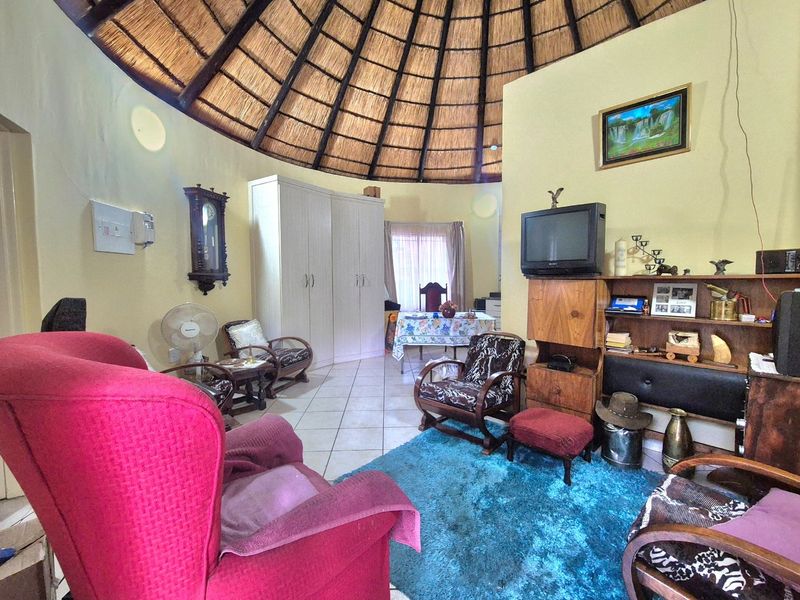 A living area featuring a distinctive high thatched ceiling and tiled flooring, offering a unique architectural character.