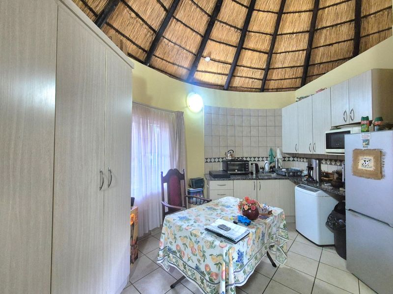 A kitchen area featuring a unique circular layout with a high thatched ceiling, built-in cabinetry, granite countertops, and tiled finishes.