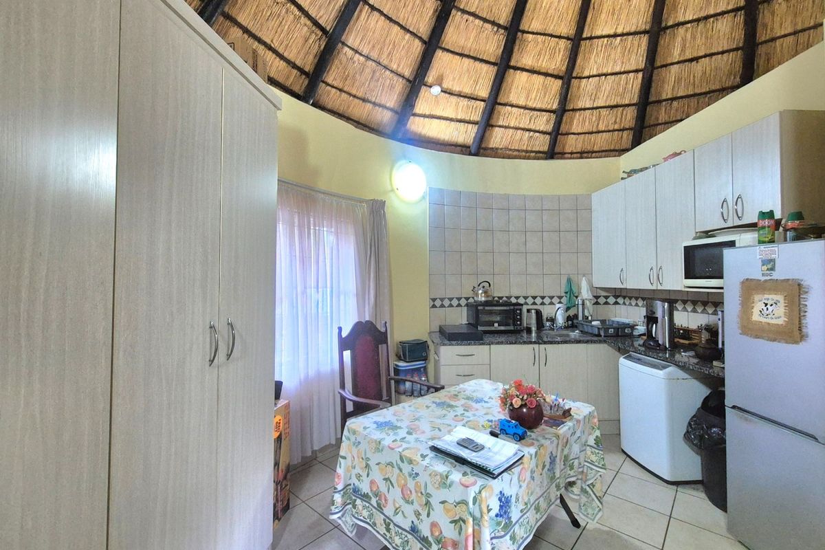 A kitchen area featuring a unique circular layout with a high thatched ceiling, built-in cabinetry, granite countertops, and tiled finishes.