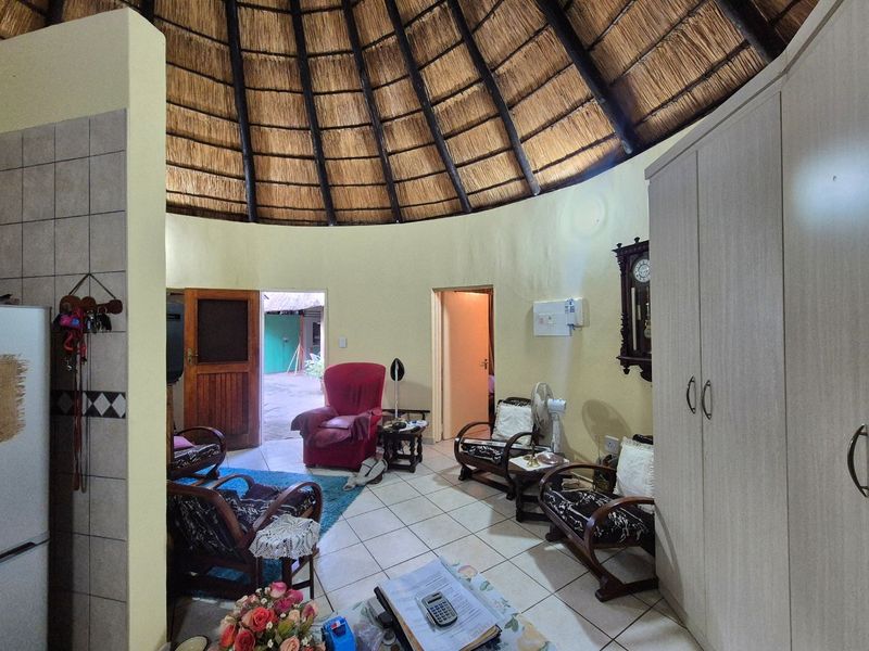 A circular living area featuring a traditional thatched roof, tiled flooring, and built-in storage cupboards.