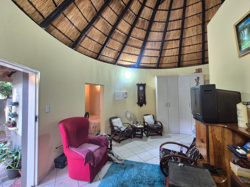 A circular living room featuring a traditional thatched roof, tiled flooring, and built-in wardrobe storage.
