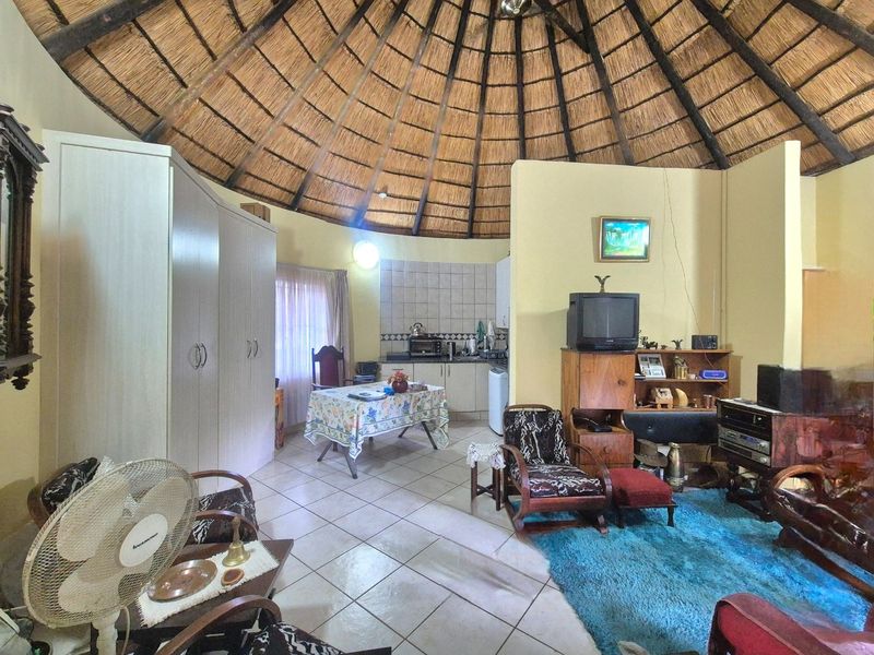 Open-plan living area featuring a distinctive thatched roof, tiled flooring, and a compact kitchen corner with built-in cabinetry.