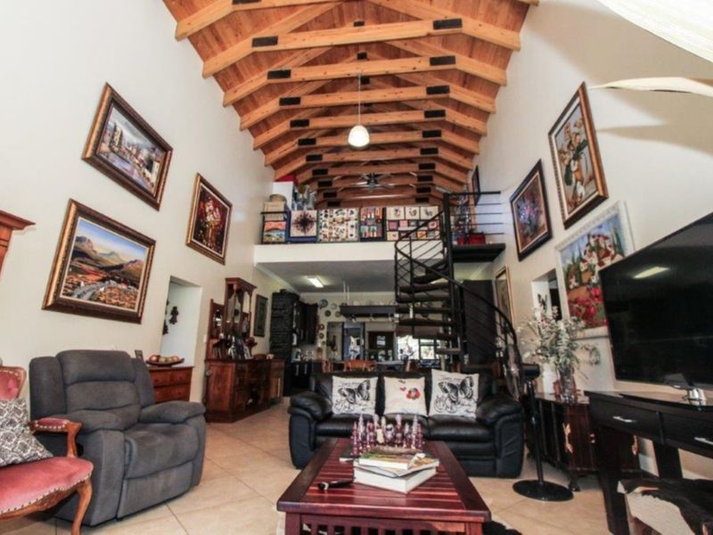 Spacious open-plan living area featuring high vaulted ceilings with exposed timber rafters, a mezzanine level, and a striking spiral staircase.