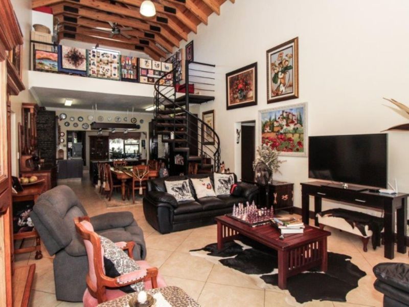 Spacious open-plan living area featuring high vaulted ceilings with exposed timber beams, a central spiral staircase, and a mezzanine level overlooking the main space.