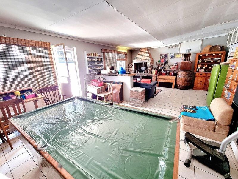 Spacious living area featuring a built-in brick fireplace and tiled flooring, offering a versatile space for entertainment and relaxation.