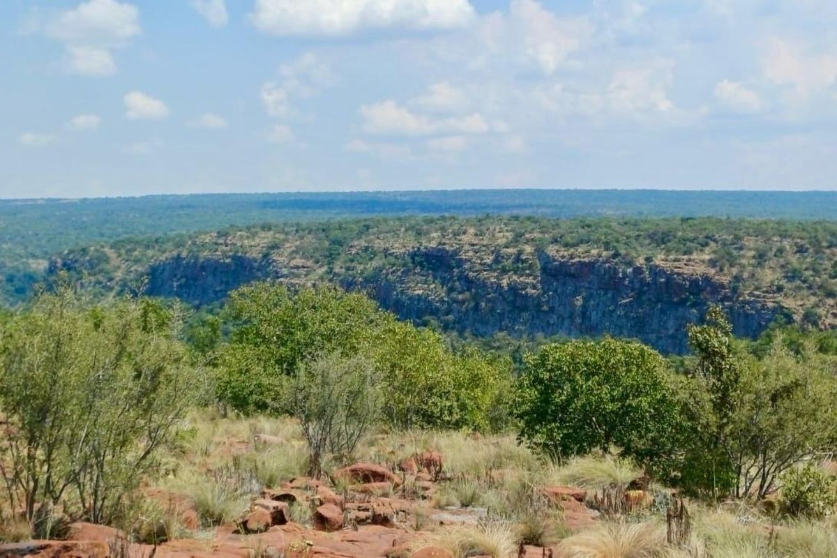 A scenic landscape view overlooking a natural rocky escarpment and expansive bushveld terrain.