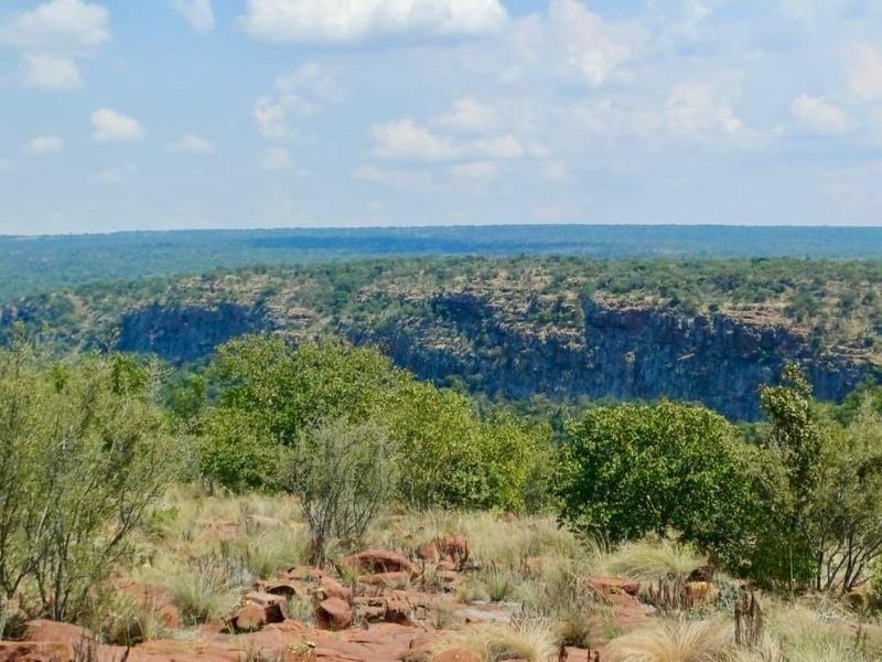A scenic landscape view overlooking a natural rocky escarpment and expansive bushveld terrain.