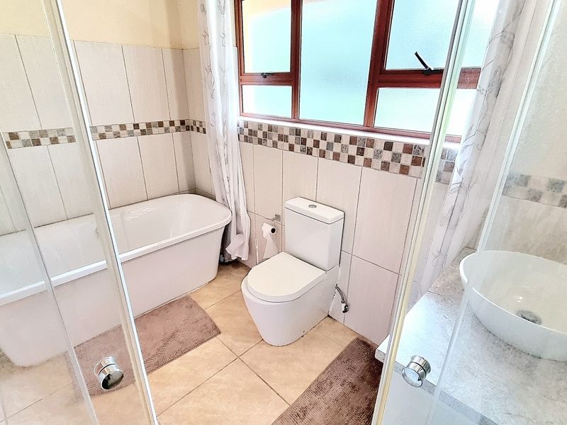 A functional bathroom featuring a freestanding bathtub, a vessel sink vanity, a toilet, and a glass-enclosed shower area with tiled finishes.
