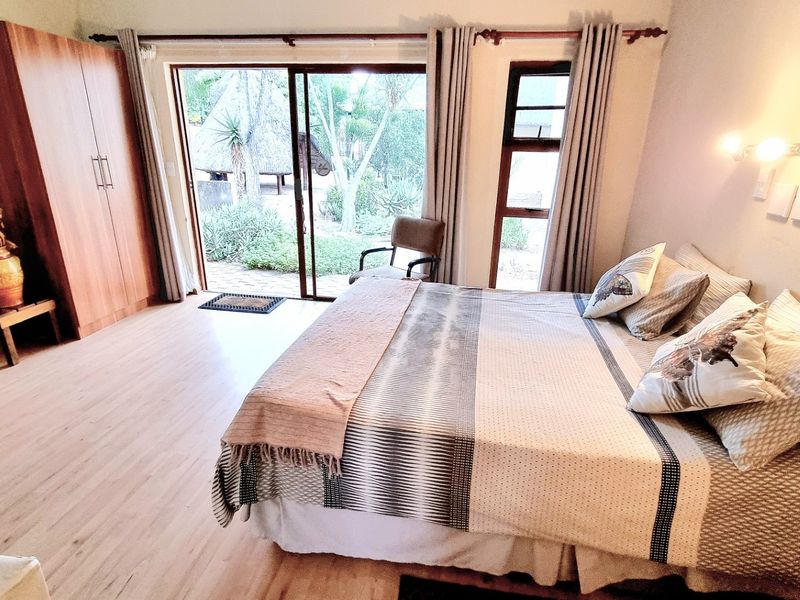 Spacious bedroom featuring laminate flooring, a built-in wardrobe, and large sliding glass doors providing direct access to the garden area.