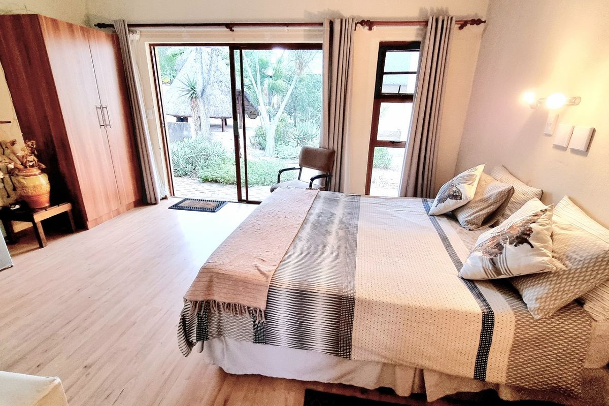Spacious bedroom featuring laminate flooring, a built-in wardrobe, and large sliding glass doors providing direct access to the garden area.