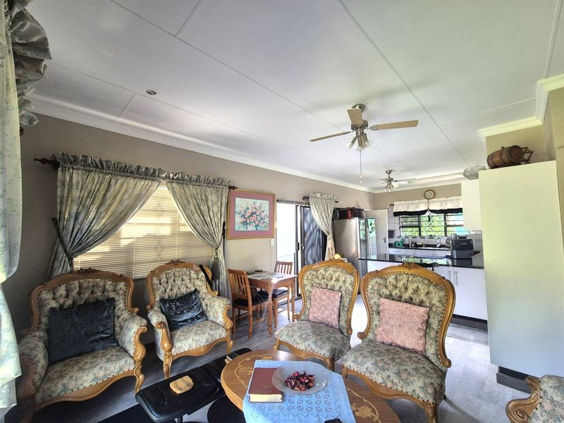 Open-plan living and kitchen area featuring a ceiling fan, neutral wall tones, and direct access to the exterior via a sliding glass door.