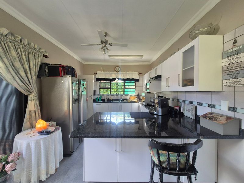 A functional kitchen featuring granite countertops, ample built-in cabinetry, a double sink, and a ceiling fan, offering a practical layout for daily use.