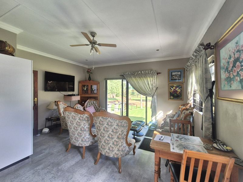 A living room featuring laminate flooring, a ceiling fan, and a sliding glass door providing access to the outdoor area.