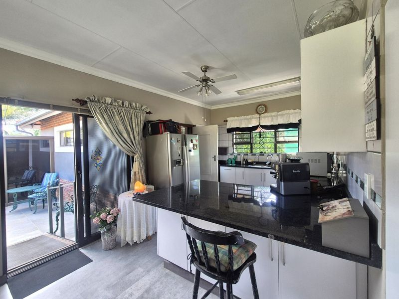 A functional kitchen featuring granite countertops, white cabinetry, and direct access to an outdoor patio area through sliding glass doors.