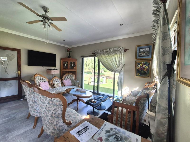 A comfortable living room featuring laminate flooring, a ceiling fan, and large sliding glass doors that provide natural light and access to the garden.