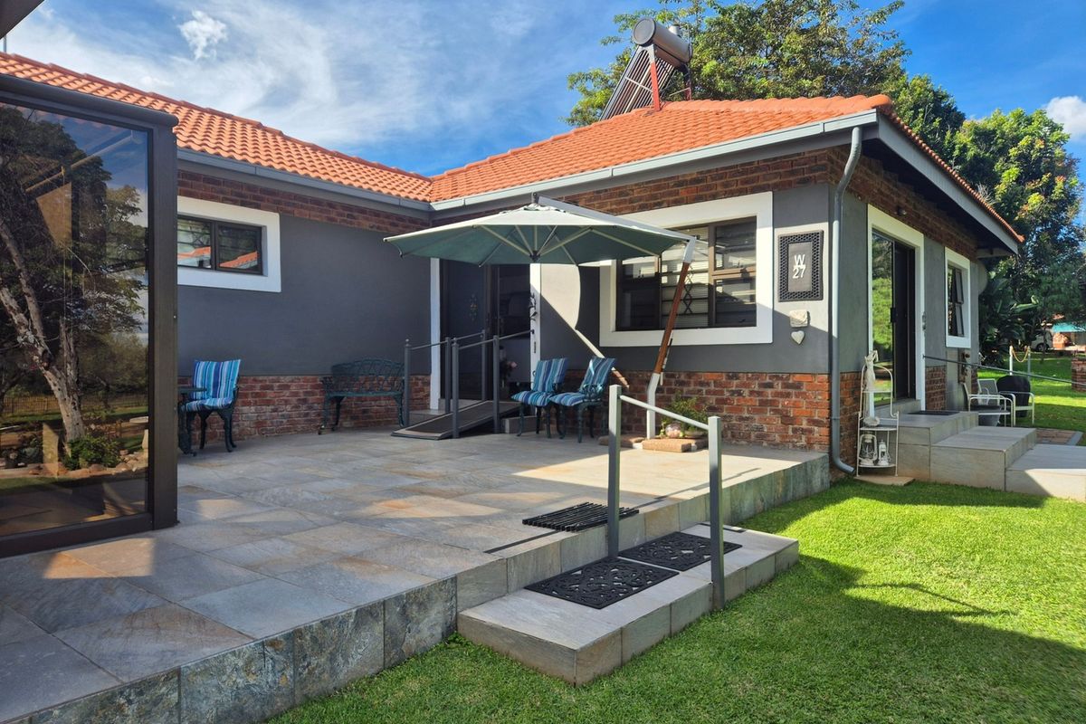 A well-maintained rear patio area featuring tiled flooring, brick and rendered walls, a solar water heater, and accessible ramp entry.