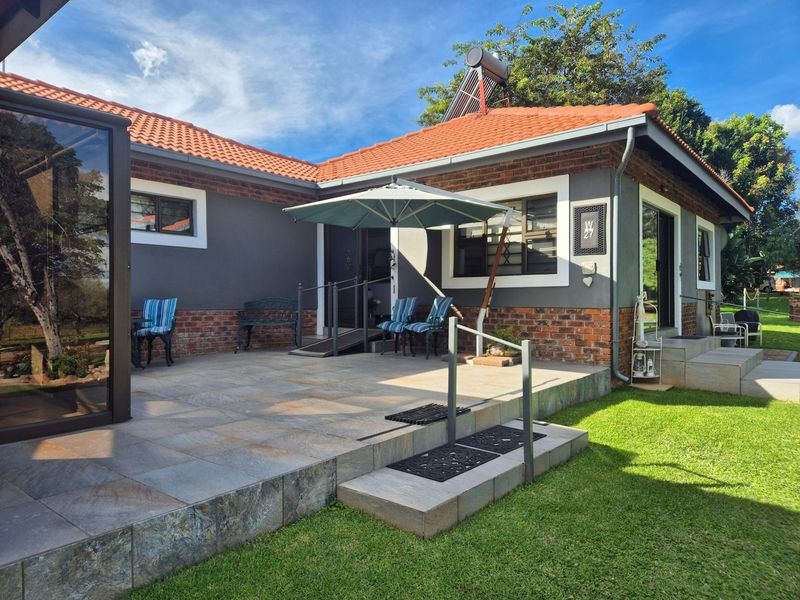 A well-maintained rear patio area featuring tiled flooring, brick and rendered walls, a solar water heater, and accessible ramp entry.
