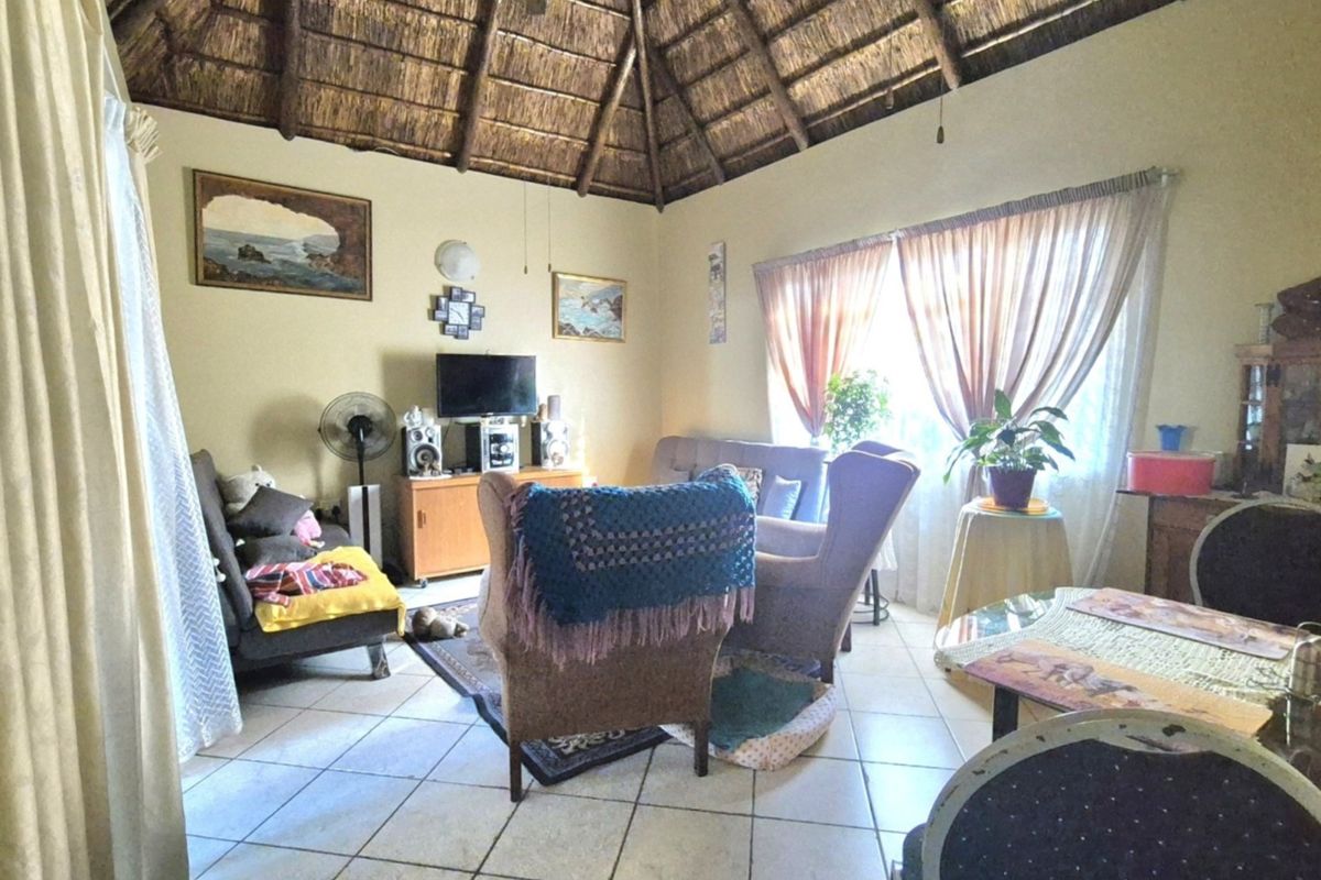 A living room featuring a traditional thatched roof with exposed timber rafters and ceramic floor tiles.