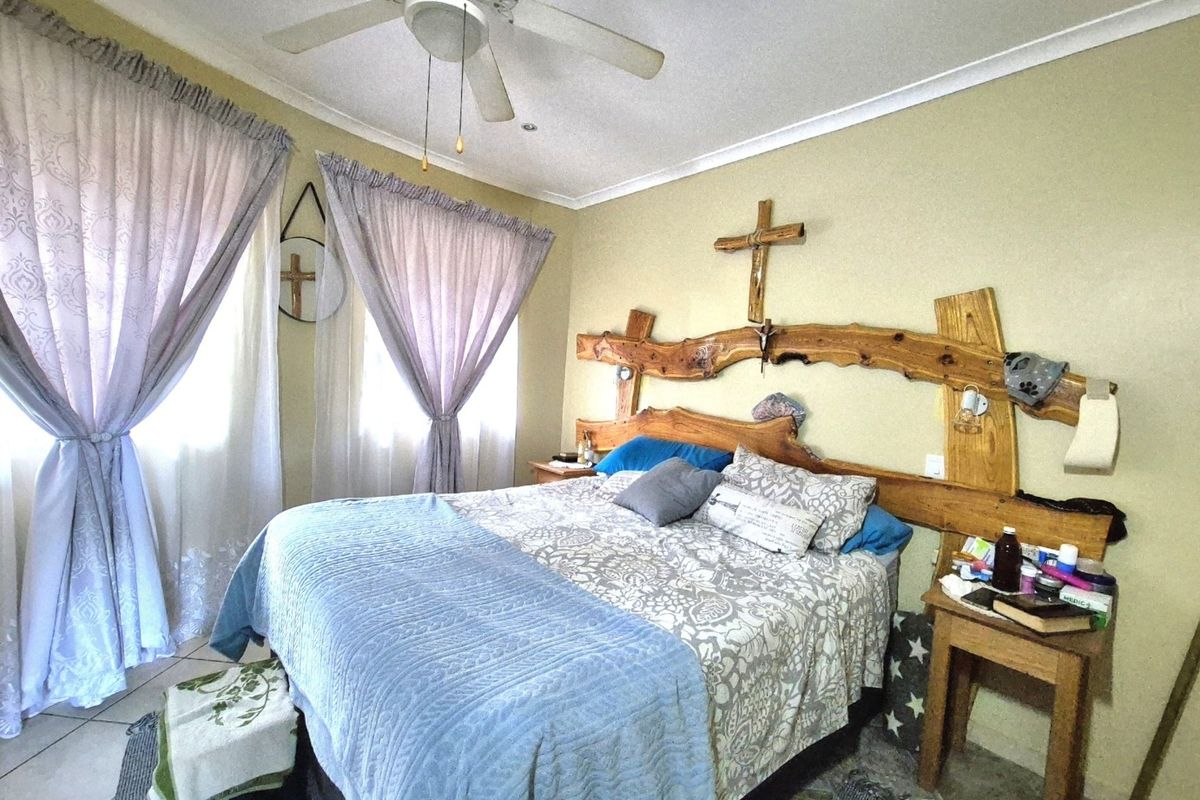 A bedroom featuring tiled flooring and a ceiling fan, providing a functional space with neutral wall tones.