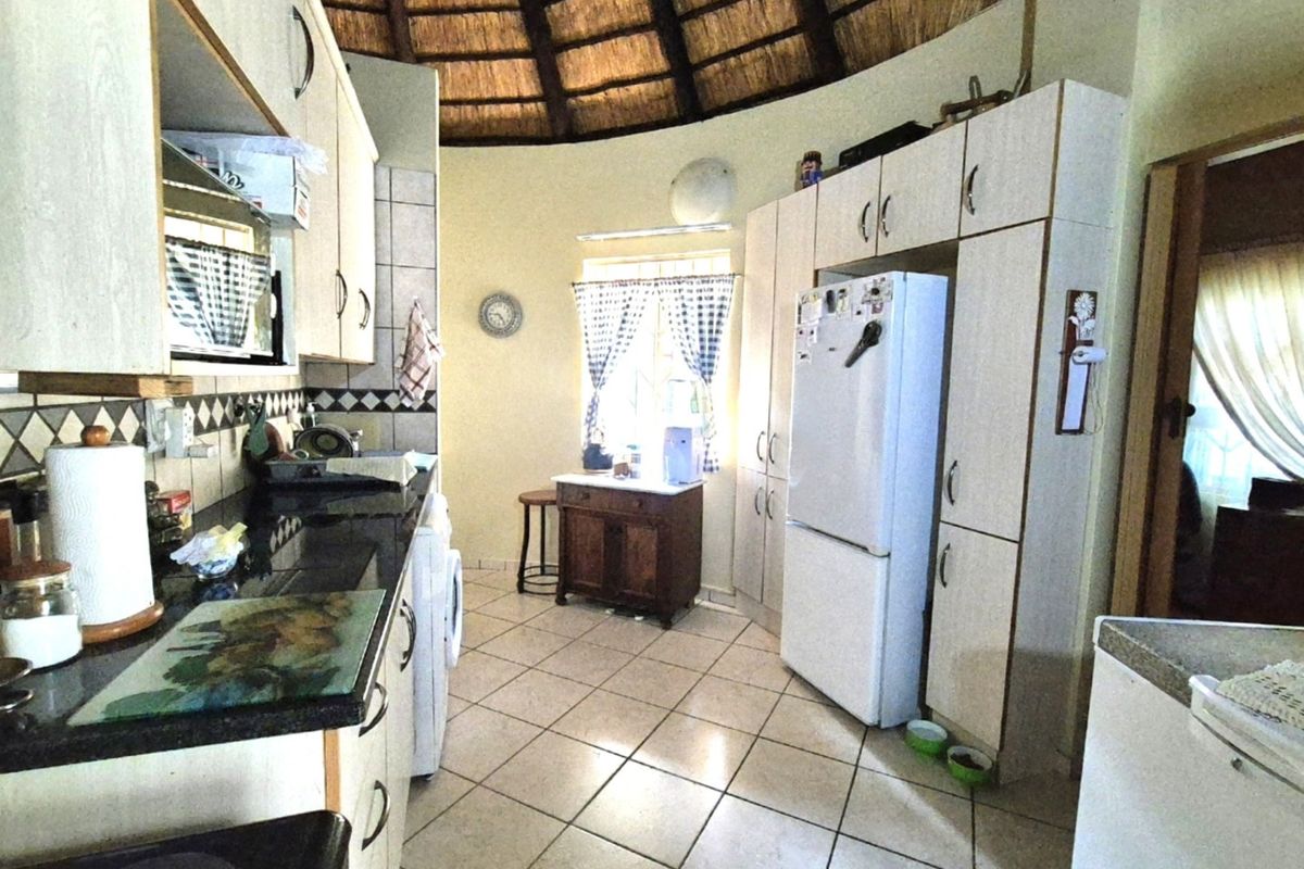 A functional kitchen featuring granite countertops, built-in cabinetry, and a unique vaulted thatch ceiling, offering a rustic aesthetic with practical storage space.