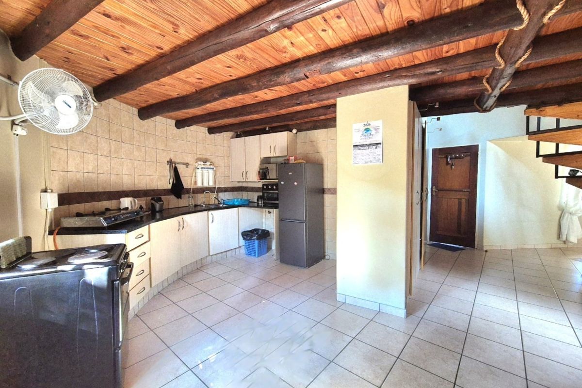 Kitchen featuring exposed timber ceiling beams, tiled flooring, and built-in cabinetry with a tiled backsplash.